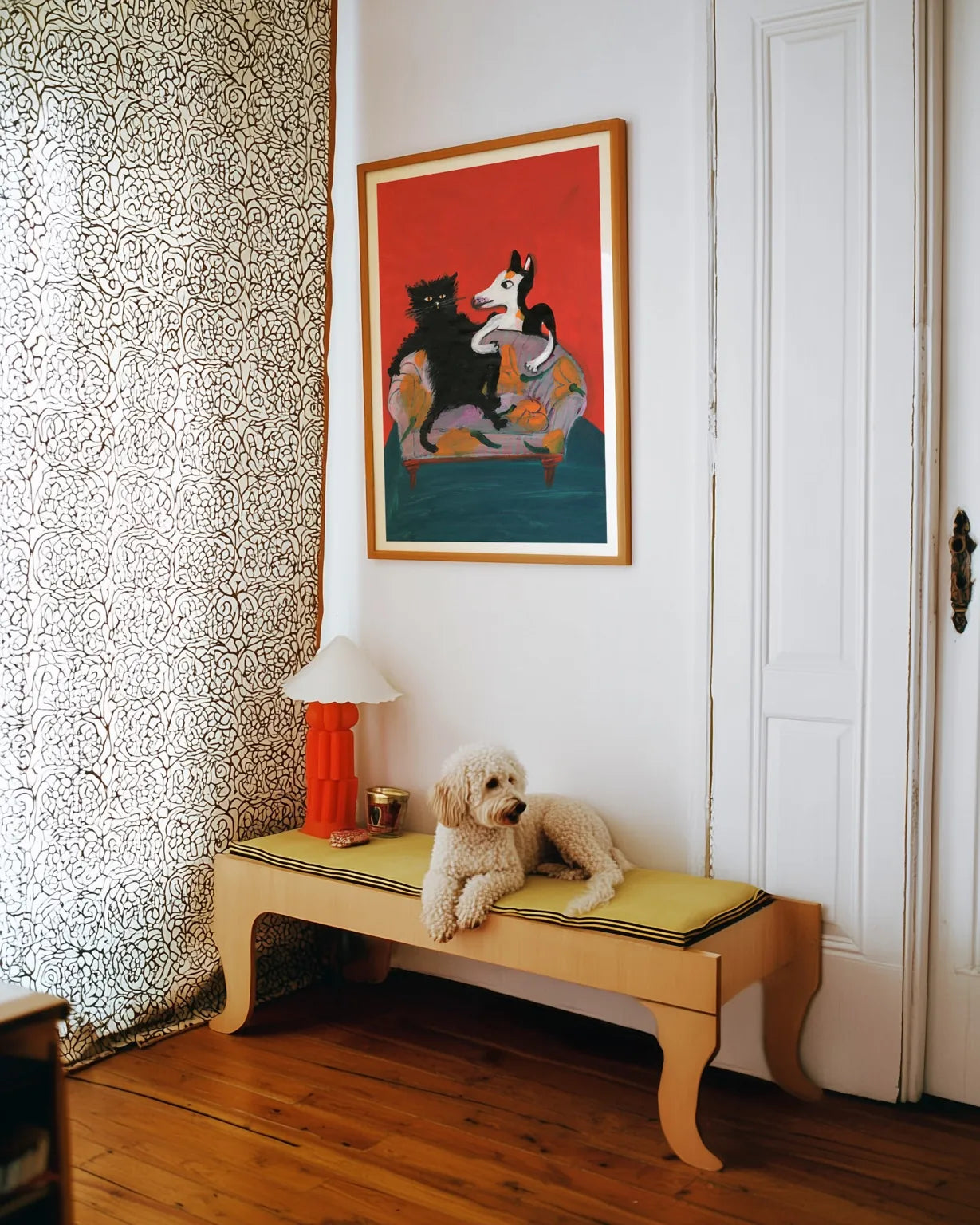 Plakat “Familieportræt” af Thomas Winding ophængt i hjem med bænk, hund og varm, personlig indretning.